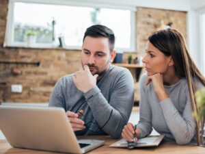 Couple reviewing financial documents during a divorce, highlighting the importance of agreeing a settlement early to avoid legal disputes.