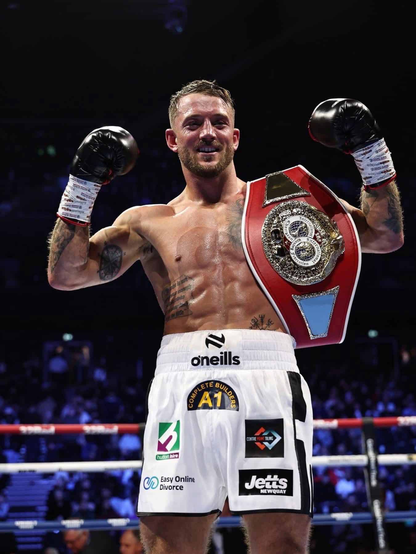 Brad Pauls celebrating after his title win in Manchester, wearing boxing shorts with Easy Online Divorce branding visible on the front.